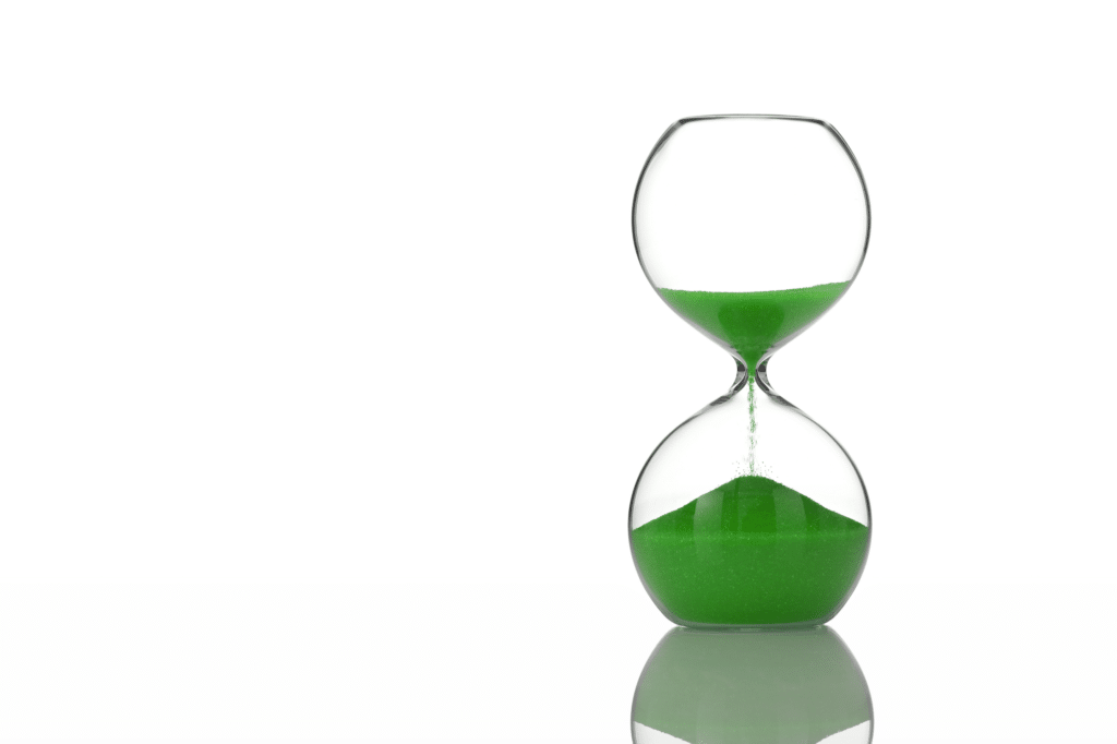Photograph of an hourglass with green sand inside it. Symbolic of divorce and the time required to pass before applying in Australia.